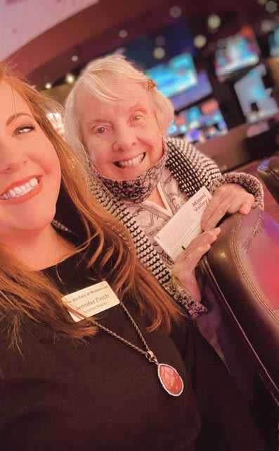 Two women smiling at a social event.
