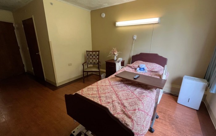 A simple hospital room with a single bed and basic furnishings.