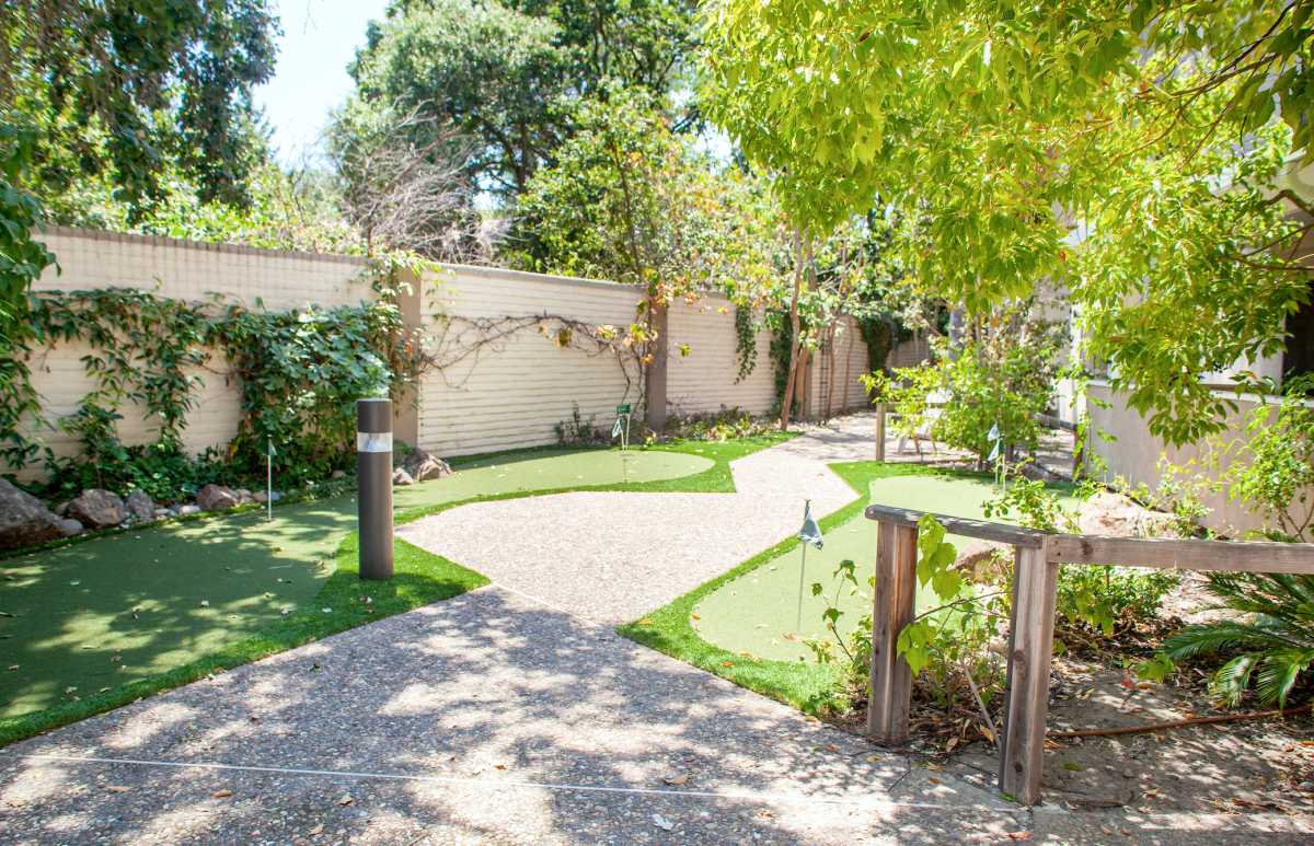 A serene garden with a mini golf course surrounded by lush greenery.