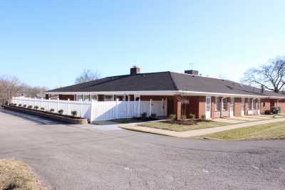 A single-story residential building with a sloped roof and a front yard.