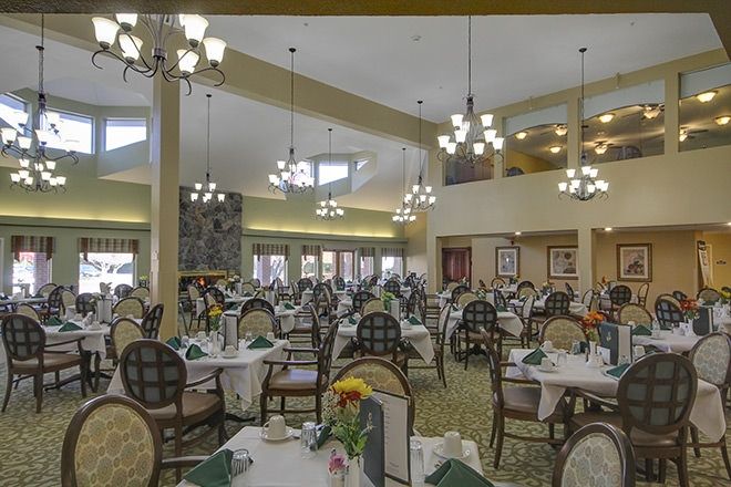 A spacious dining hall with neatly arranged tables and elegant chandeliers.