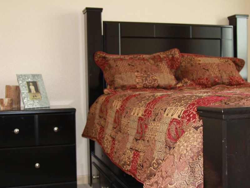 A cozy bedroom featuring a dark wooden bed with patterned bedding and a matching nightstand.