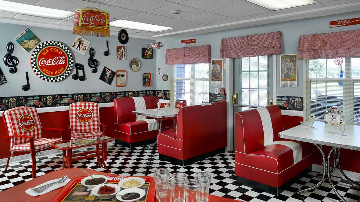 A classic 50s-style diner with red booths and a black-and-white checkered floor, adorned with retro decor and memorabilia.