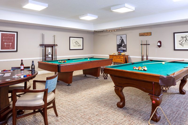 A well-lit billiards room with two pool tables and stylish decor.