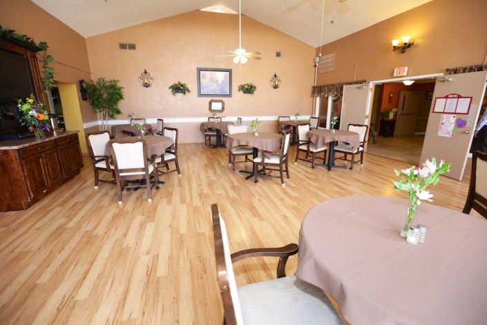 A cozy dining area with neatly arranged tables and chairs on a wooden floor.