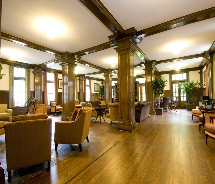 A spacious lounge area with wooden beams, comfortable seating, and large windows.