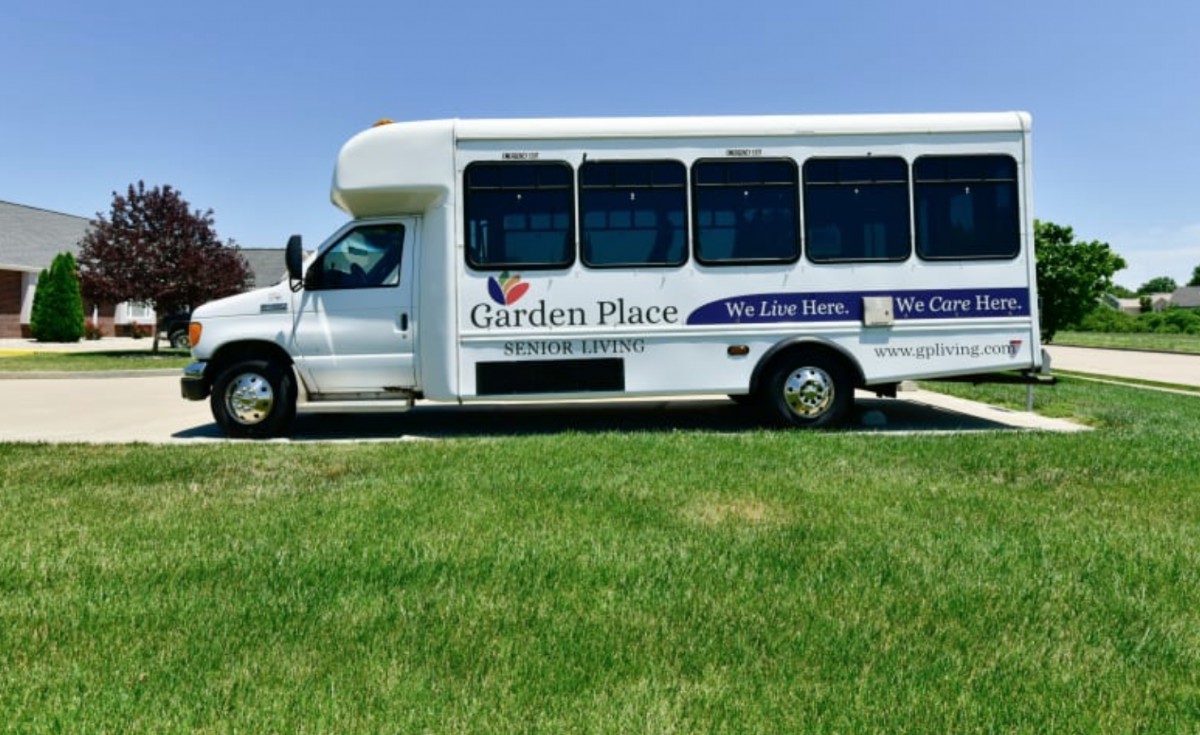 A white shuttle bus parked on a grassy area under a clear sky.