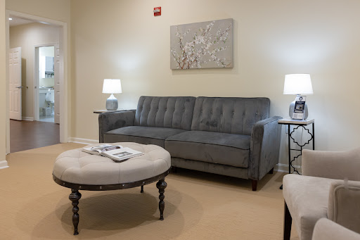 A cozy living room setup featuring a gray sofa, an ottoman, and stylish table lamps.