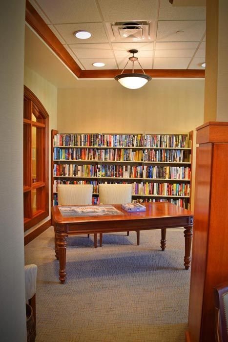 A cozy library corner with bookshelves, a wooden table, and chairs.