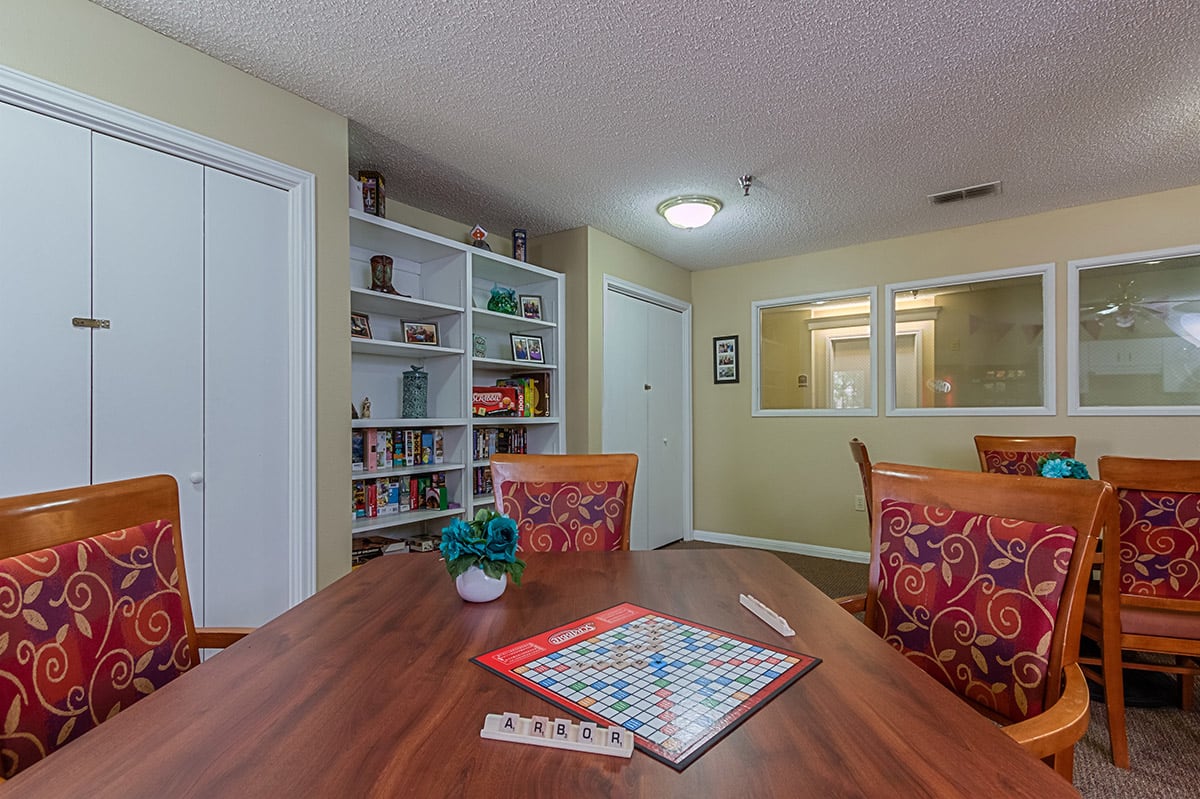 A cozy game room with a board game set up on the table next to a bookshelf.