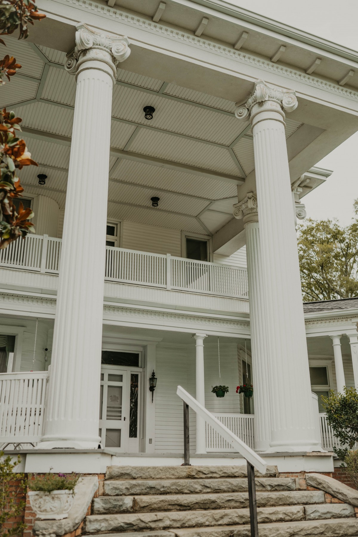 A grand house featuring tall, classical columns and a spacious porch.