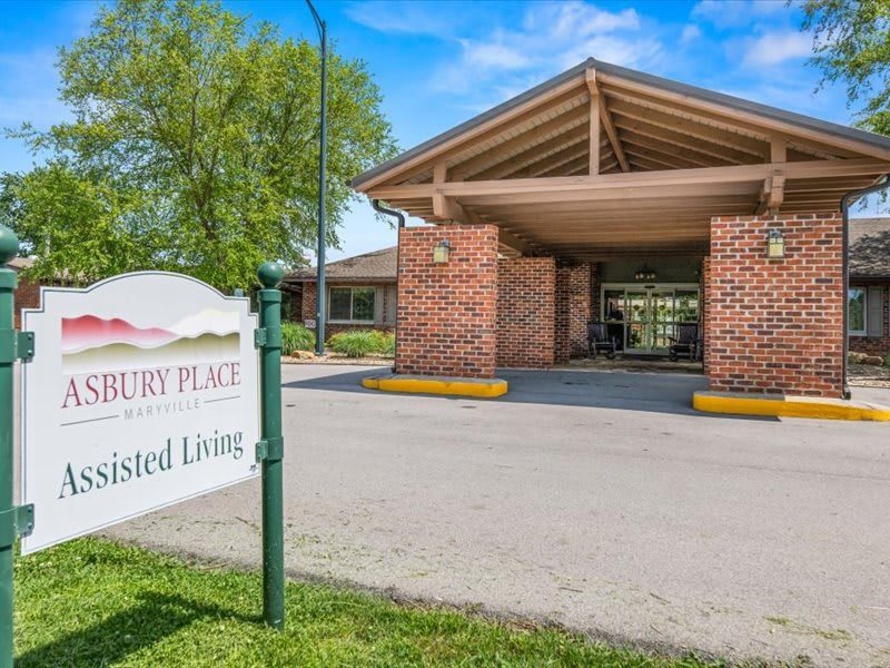 Entrance to an assisted living facility with a sign and brick pillars.