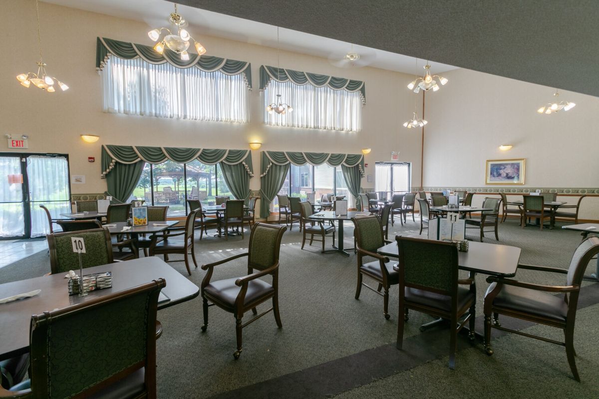 A spacious dining room with elegant furniture and large windows adorned with curtains.