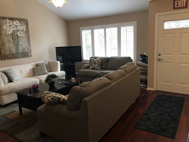 A cozy living room with sofas arranged around a coffee table and a TV near the window.