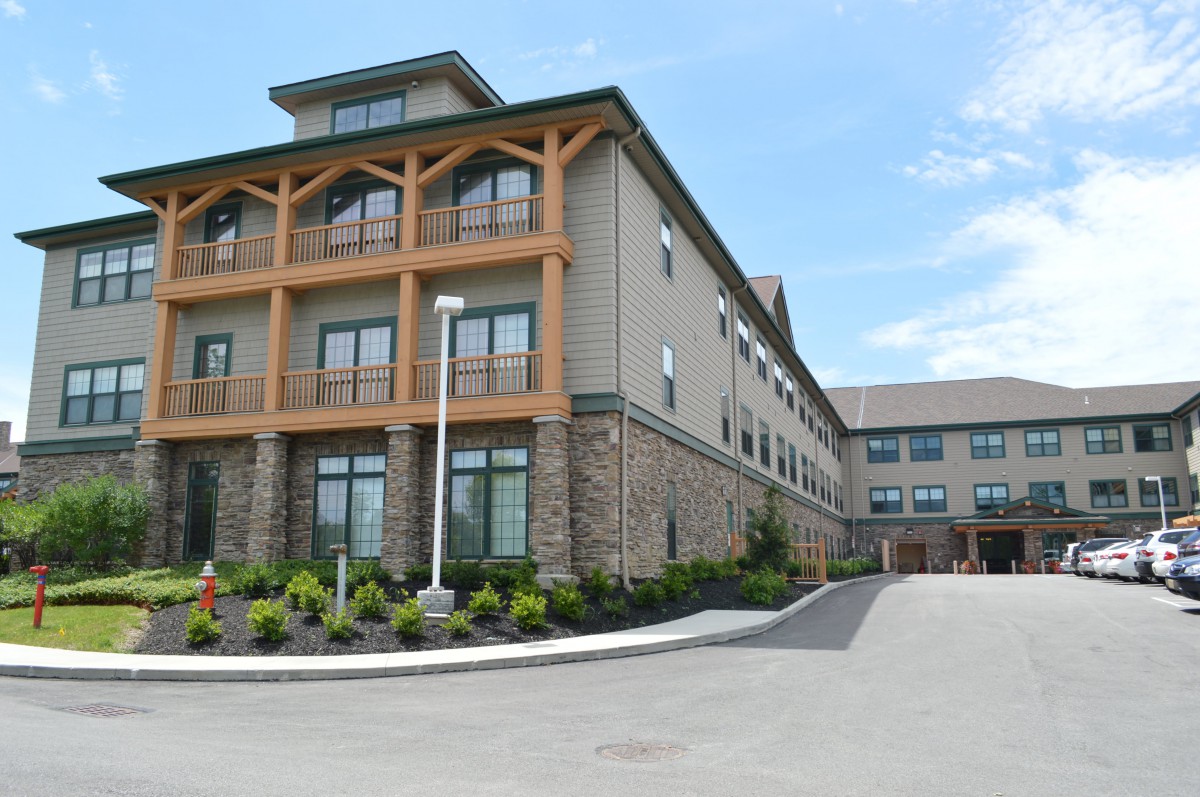 A modern hotel building with a landscaped exterior and clear sky.