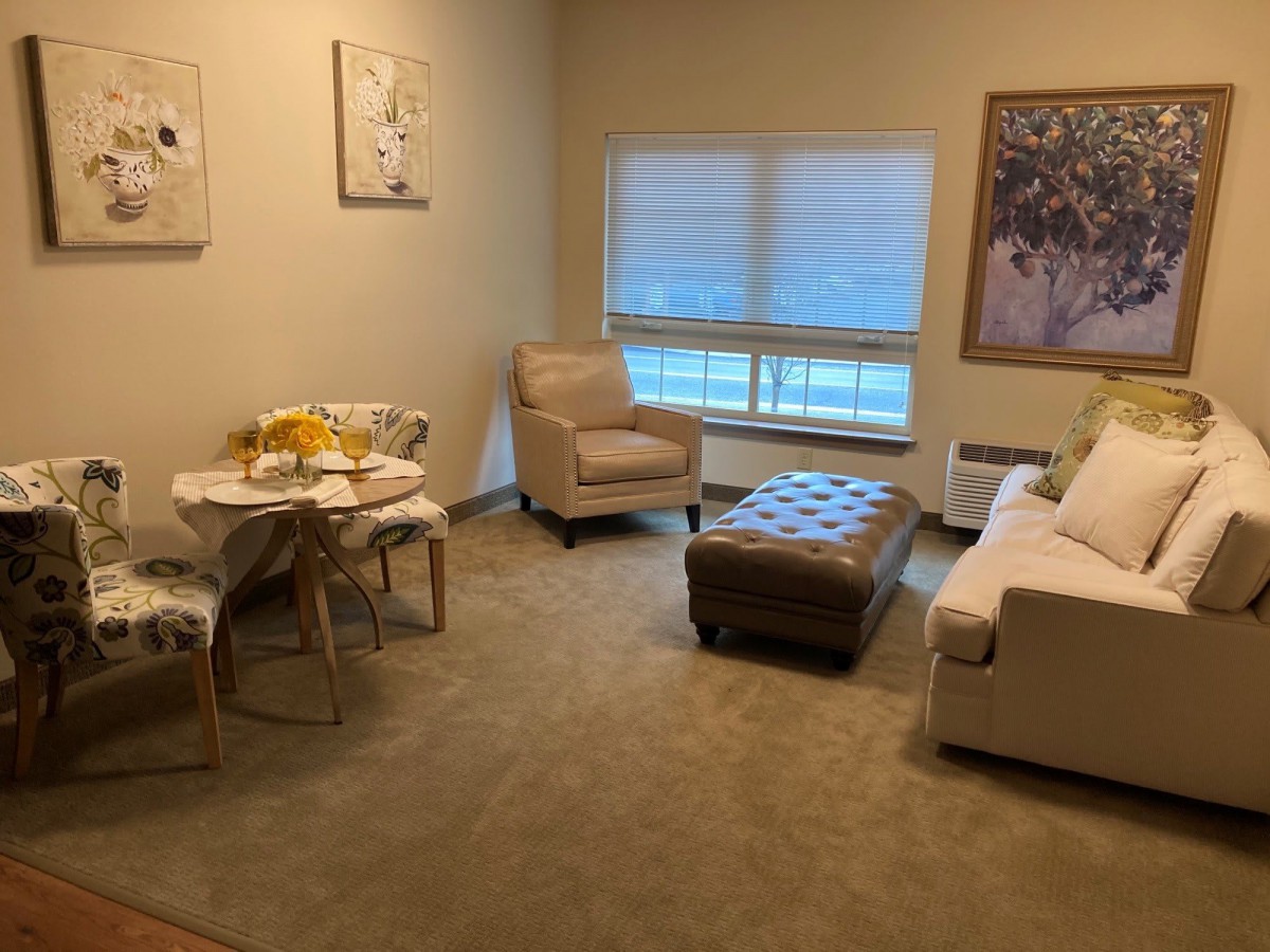 A cozy living room with a sofa, armchair, and a small dining table.