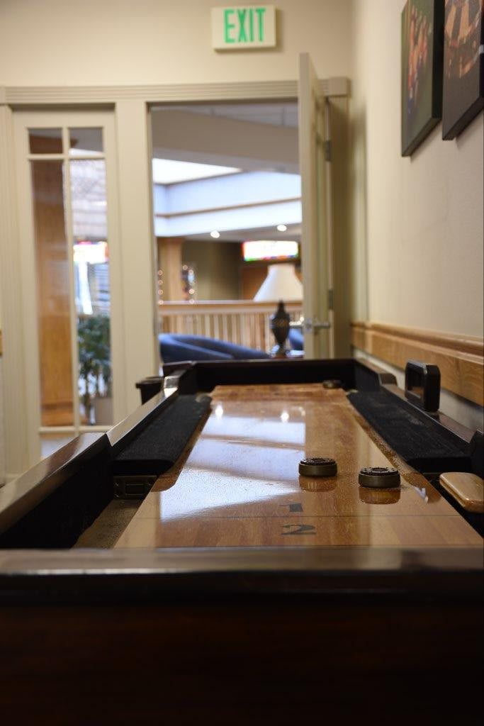 A shuffleboard table in a well-lit indoor game room.