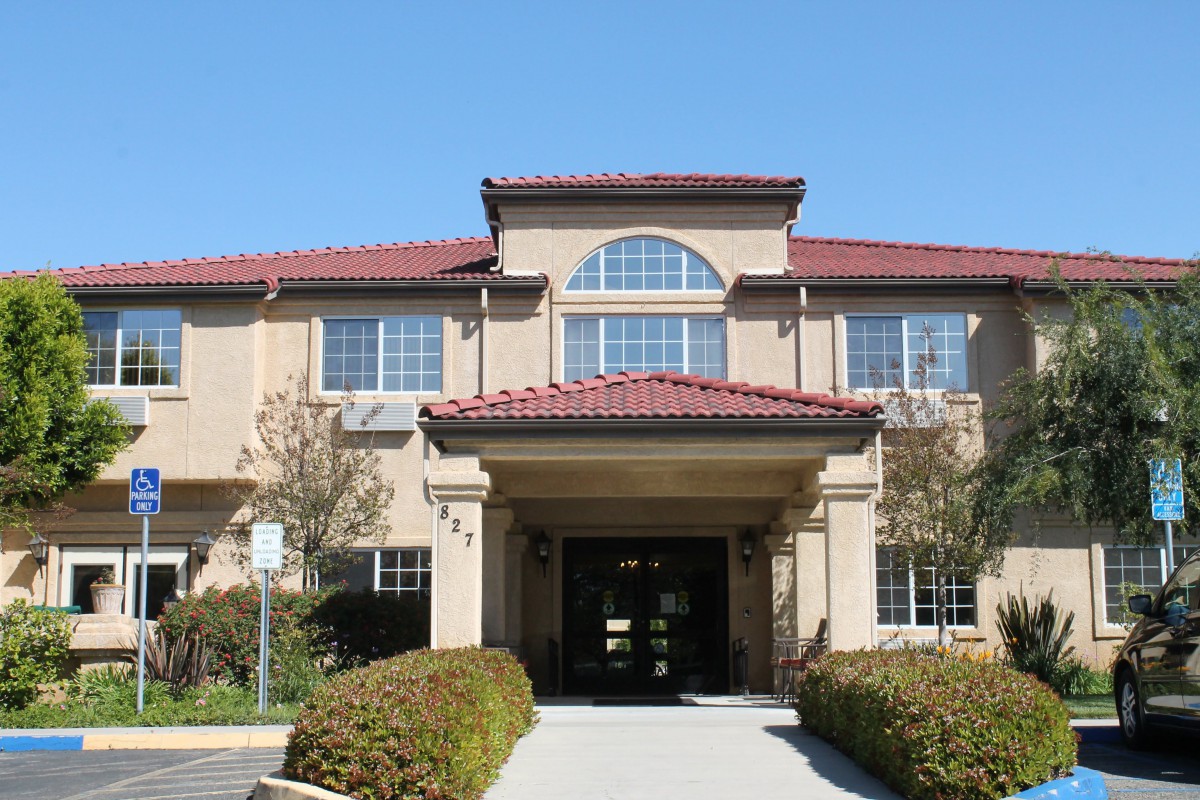 A two-story residential building with a main entrance and surrounding landscaping.