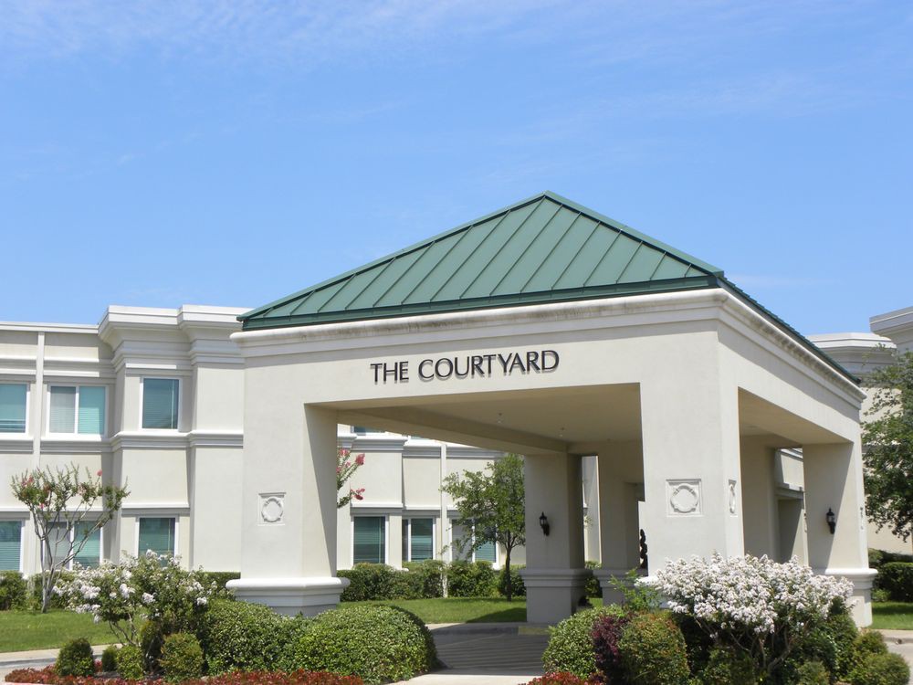 A hotel entrance with a green roof and landscaped surroundings.