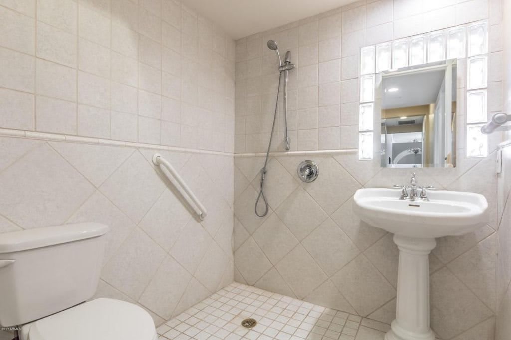 A simple bathroom with a walk-in shower, toilet, and pedestal sink.