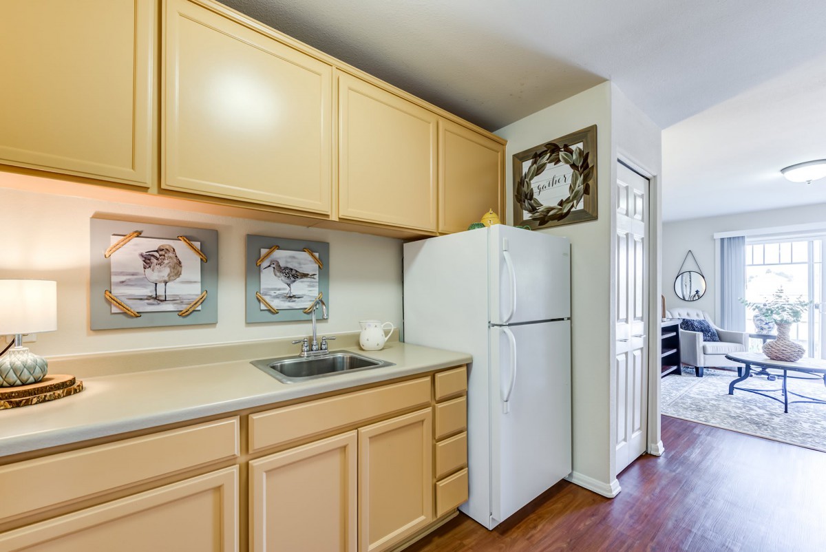 A cozy kitchen featuring light wood cabinets, a white refrigerator, and decorative wall art.
