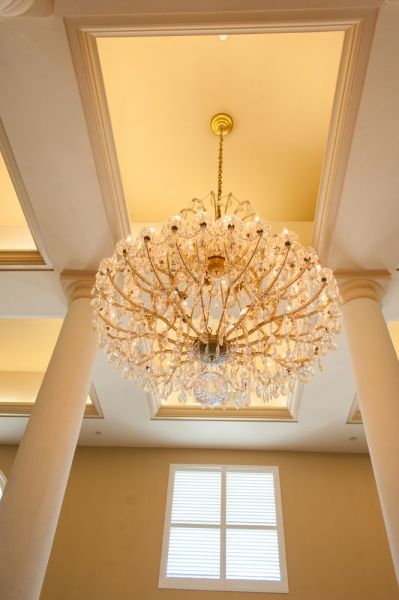 A luxurious chandelier hanging from the ceiling, surrounded by elegant columns.