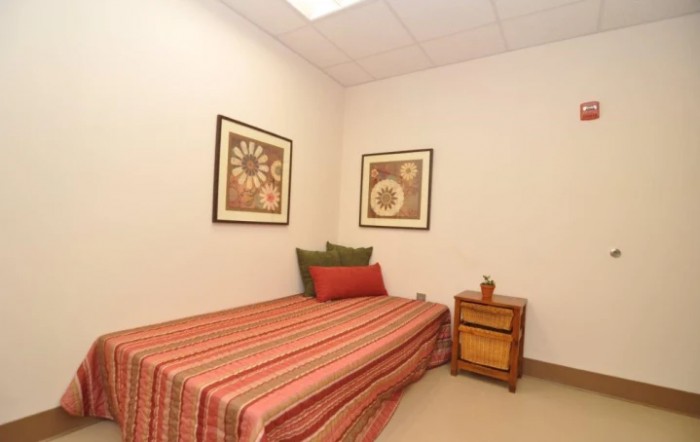A small, minimalist bedroom with a single bed and decorative artwork on the walls.
