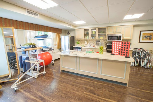 A modern kitchen space designed for rehabilitation, featuring an exercise ball and accessible appliances.