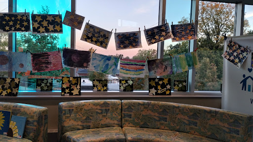 A vibrant display of children's artwork hanging by the window, creating a warm and inviting atmosphere.