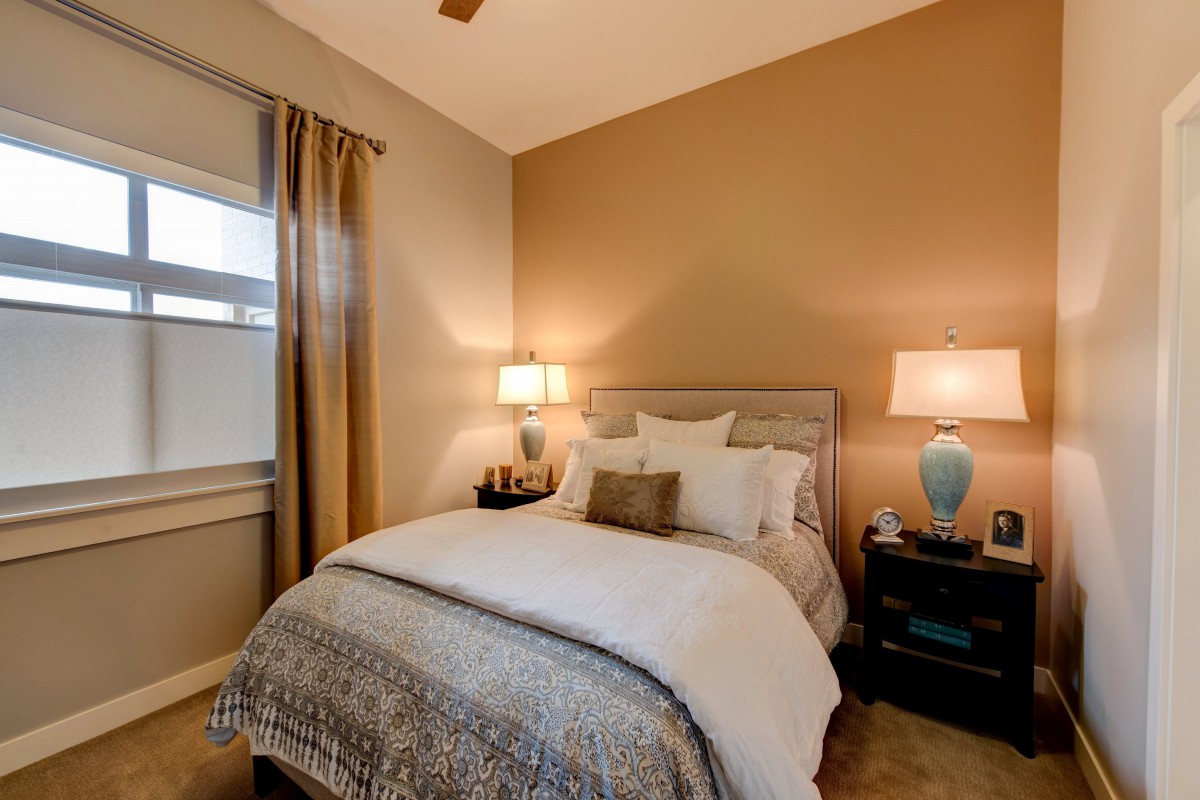 Cozy bedroom with a neatly made bed, warm lighting, and elegant decor.