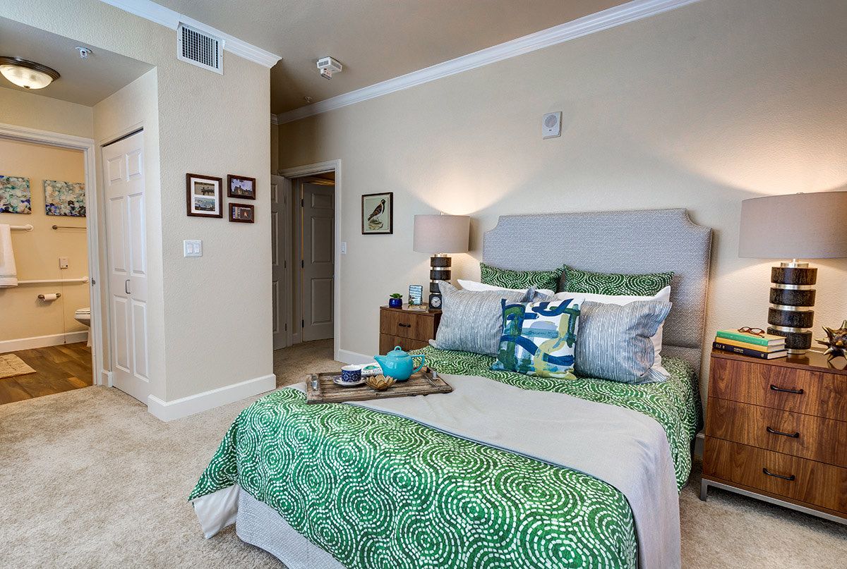 A cozy and modern bedroom featuring green bedding with decorative pillows and a stylish decor.