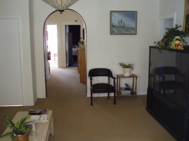 A cozy living room with an archway, featuring a chair, side table with a plant, and a television.