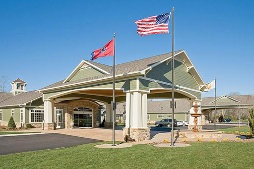 The entrance of a hotel showcasing the American and state flags against a clear blue sky.