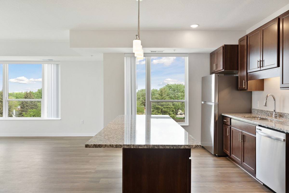 A modern kitchen with a large island, stainless steel appliances, and bright natural lighting.