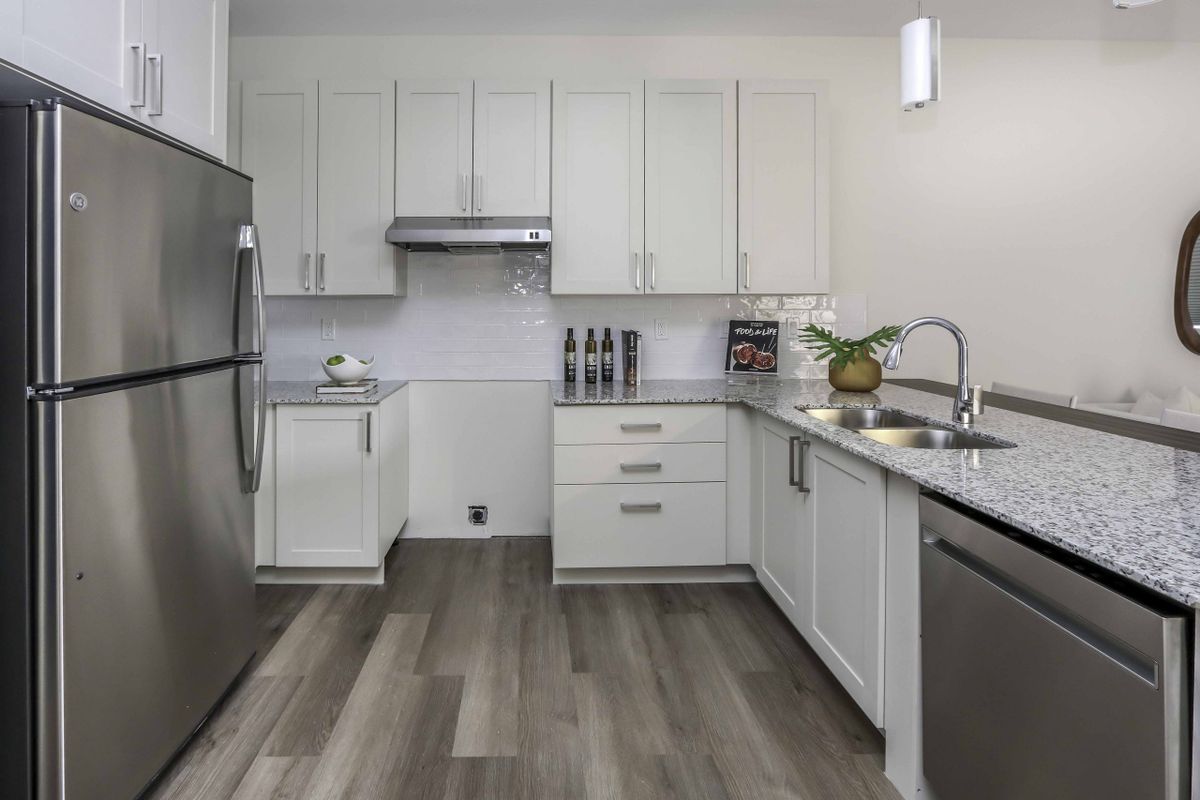 A modern kitchen with white cabinets and stainless steel appliances.