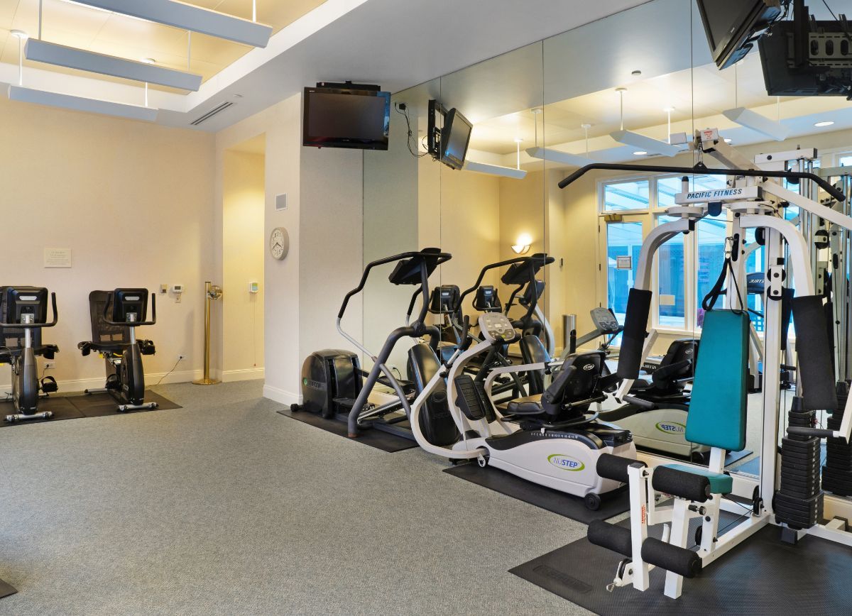 A modern gym with various exercise equipment and mirrored walls.