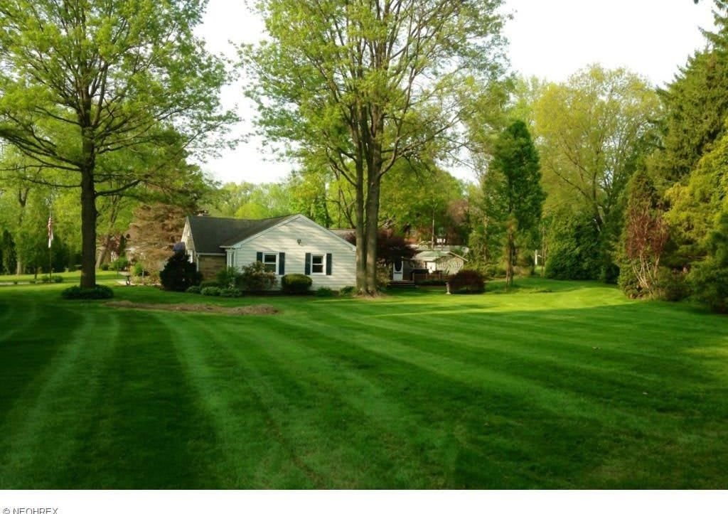 A suburban house surrounded by a neatly manicured lawn and trees.