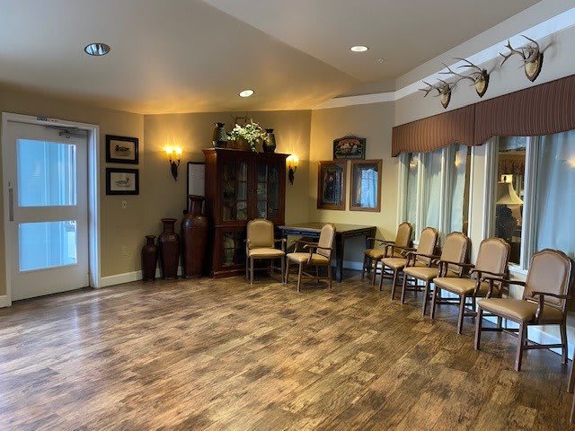 A spacious waiting room with wooden floors and arranged chairs.