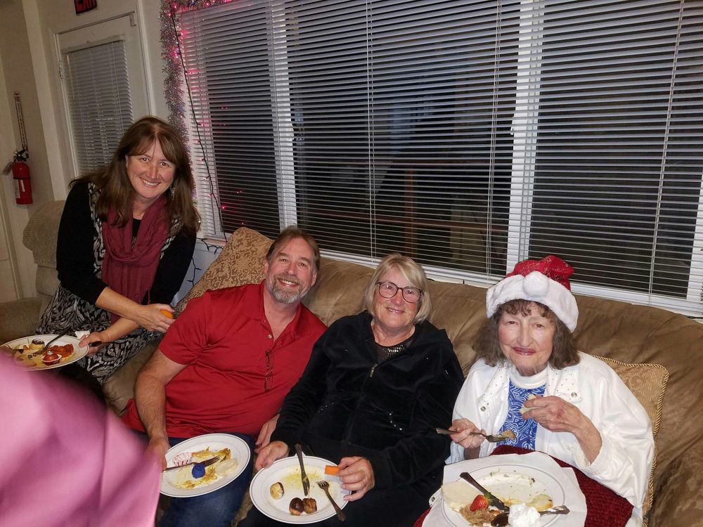 A group of four people enjoying a holiday celebration indoors, with one person wearing a Santa hat.