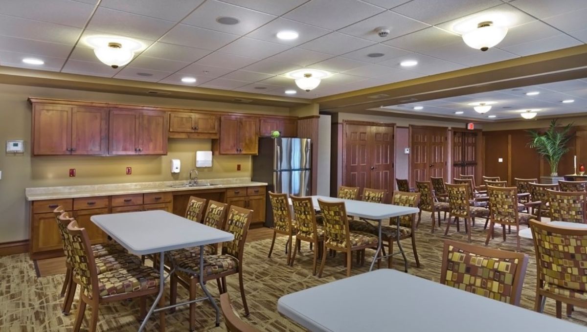 A spacious community dining room with tables, chairs, and a kitchen area.