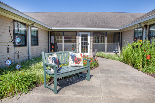 A charming outdoor seating area with a cozy bench adorned with decorative pillows, surrounded by lush greenery.