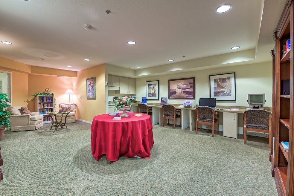 A well-lit office space with multiple workstations and a table covered with a red cloth.