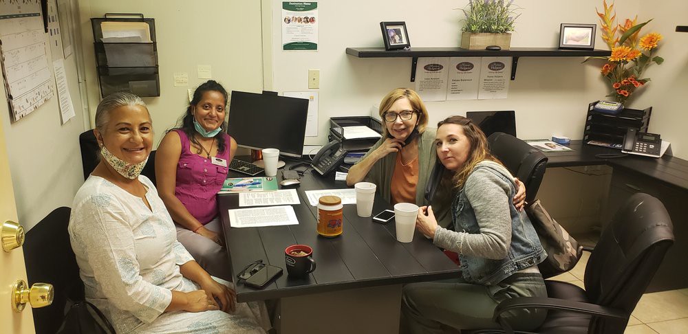 A group of people gathered around a desk for a meeting in an office setting.