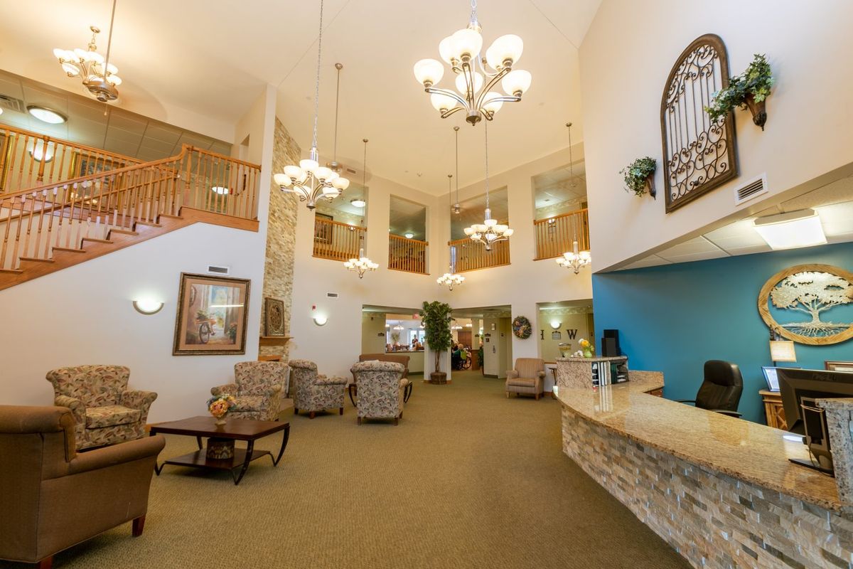 A spacious hotel lobby with elegant chandeliers, a reception desk, and comfortable seating areas.