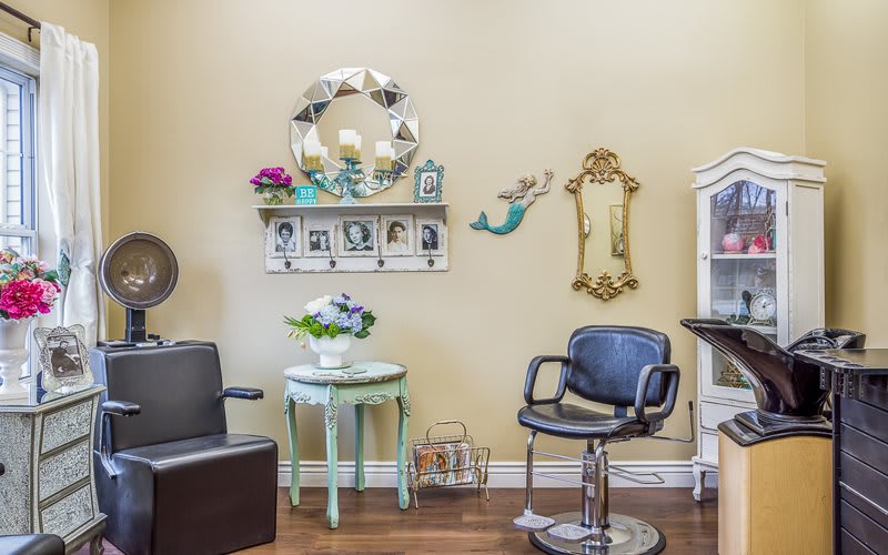 A cozy salon interior with a barber chair, decorative mirrors, and wall art.