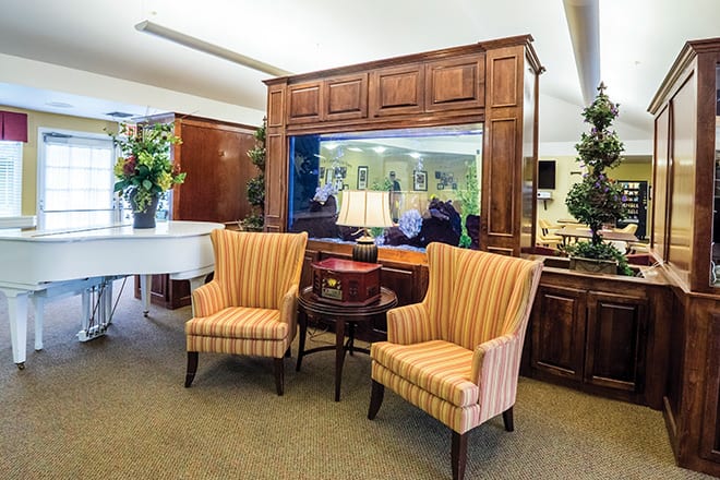 A cozy living room setup with striped armchairs, a wooden cabinet, and an aquarium centerpiece.