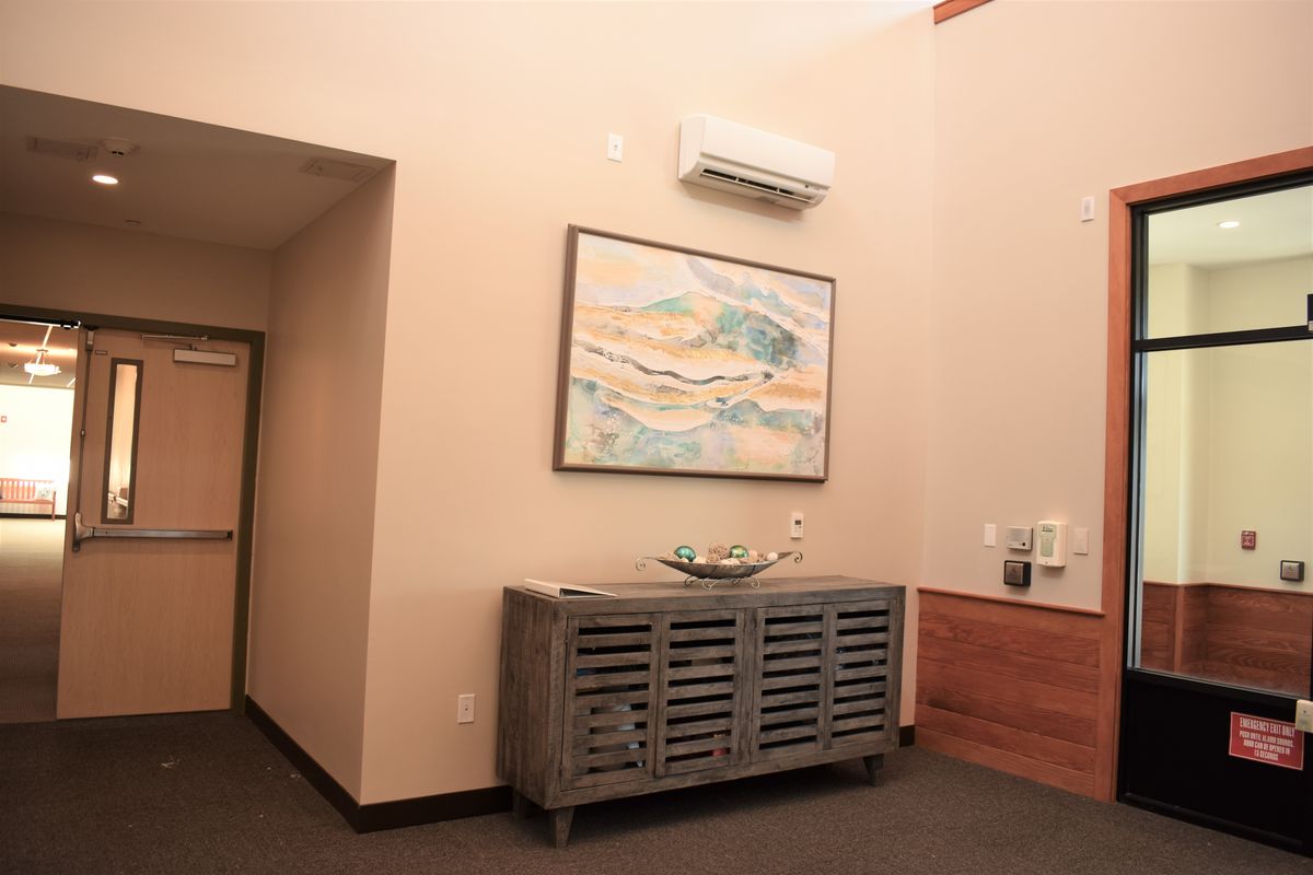 A room interior featuring a modern cabinet, a wall-mounted painting, and an air conditioning unit.