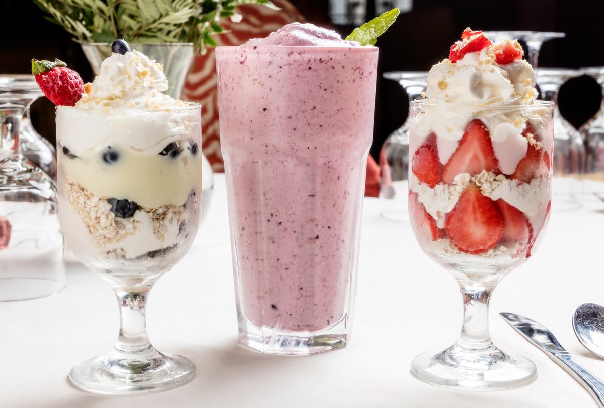 A delicious display of berry parfaits and a creamy milkshake.