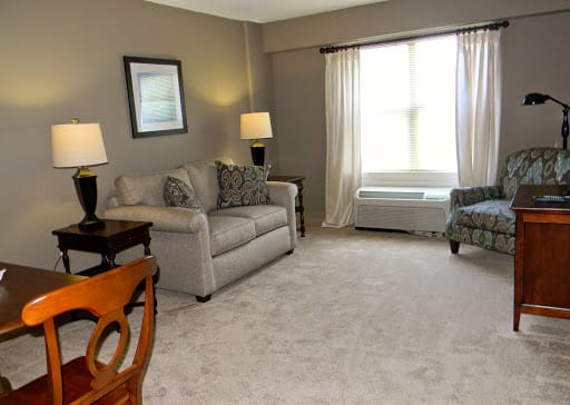 A cozy living room with a sofa, chairs, and ambient lighting from two lamps.