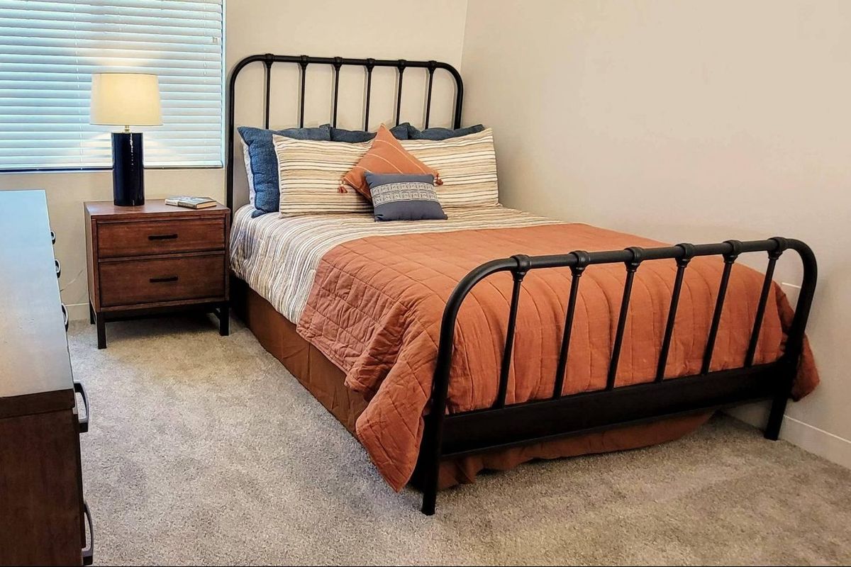 A cozy bedroom with a neatly made bed and a nightstand.